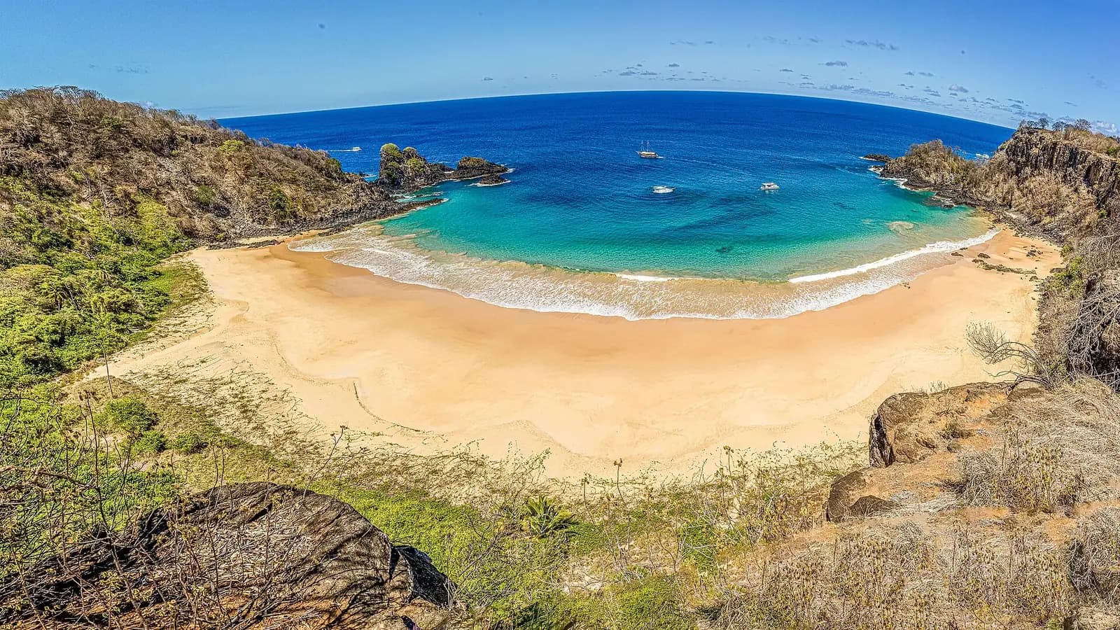 Baia do Sancho, Fernando de Noronha, Brazil - wide panorama of the cove with boats moored offshore