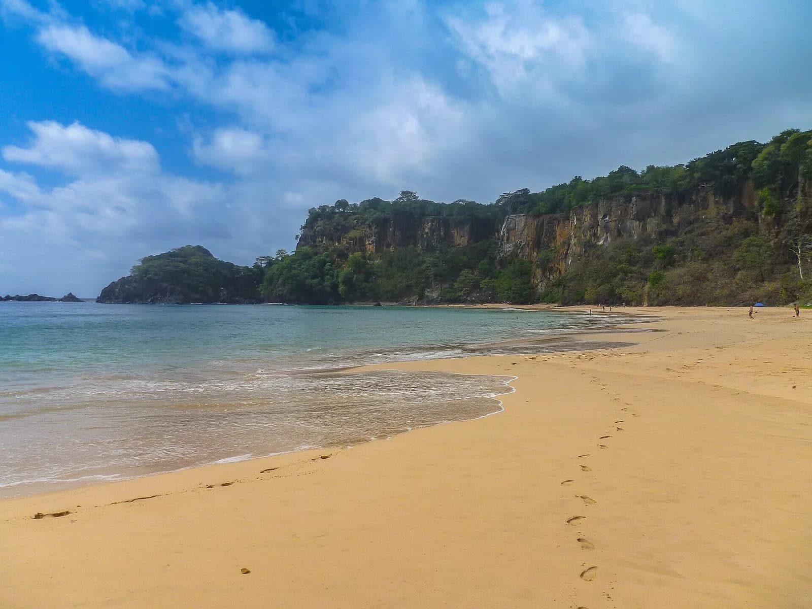 Baia do Sancho, Fernando de Noronha, Brazil - footprints along the shoreline at beach level beneath the cliffs