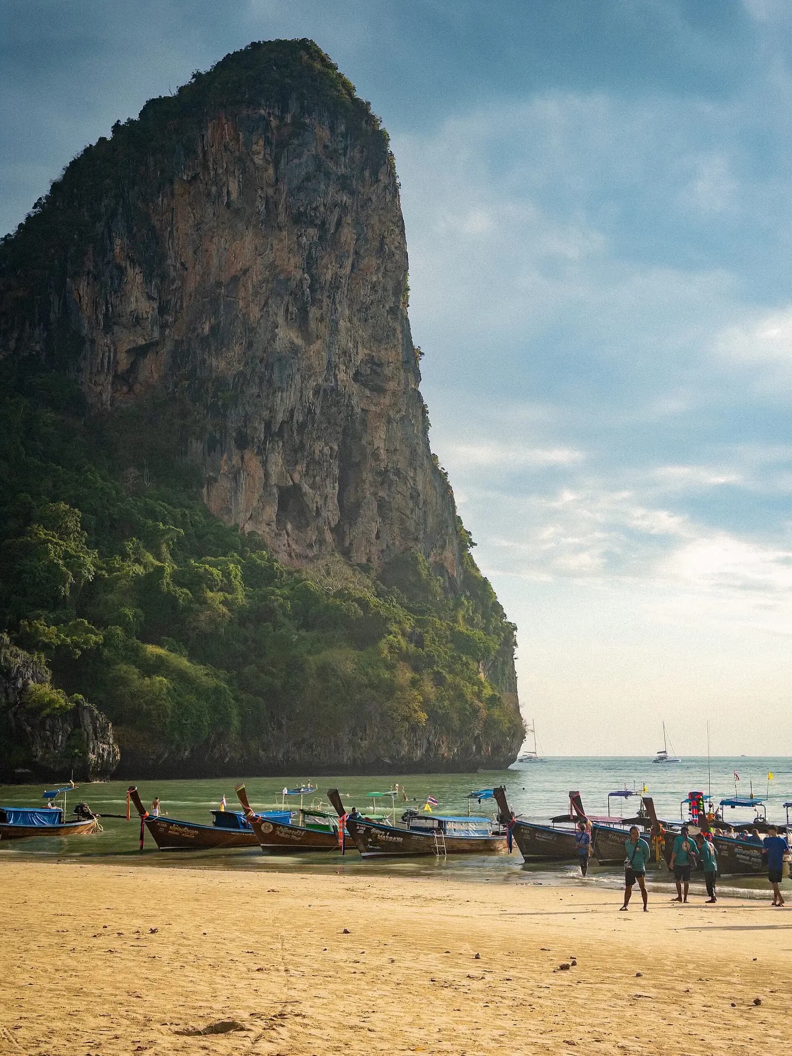 Railay Beach, Krabi, Thailand - dramatic limestone karst cliff rising above longtail boats at Railay West