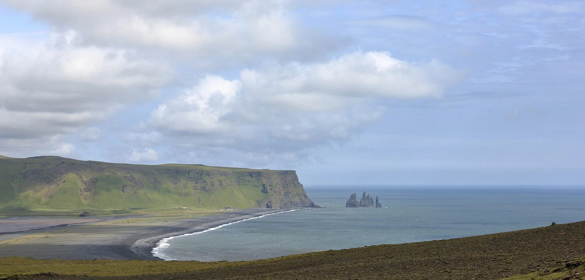 Reynisfjara, South Iceland - wide vista of the black sand crescent, sea cliffs and the Reynisdrangar sea stacks