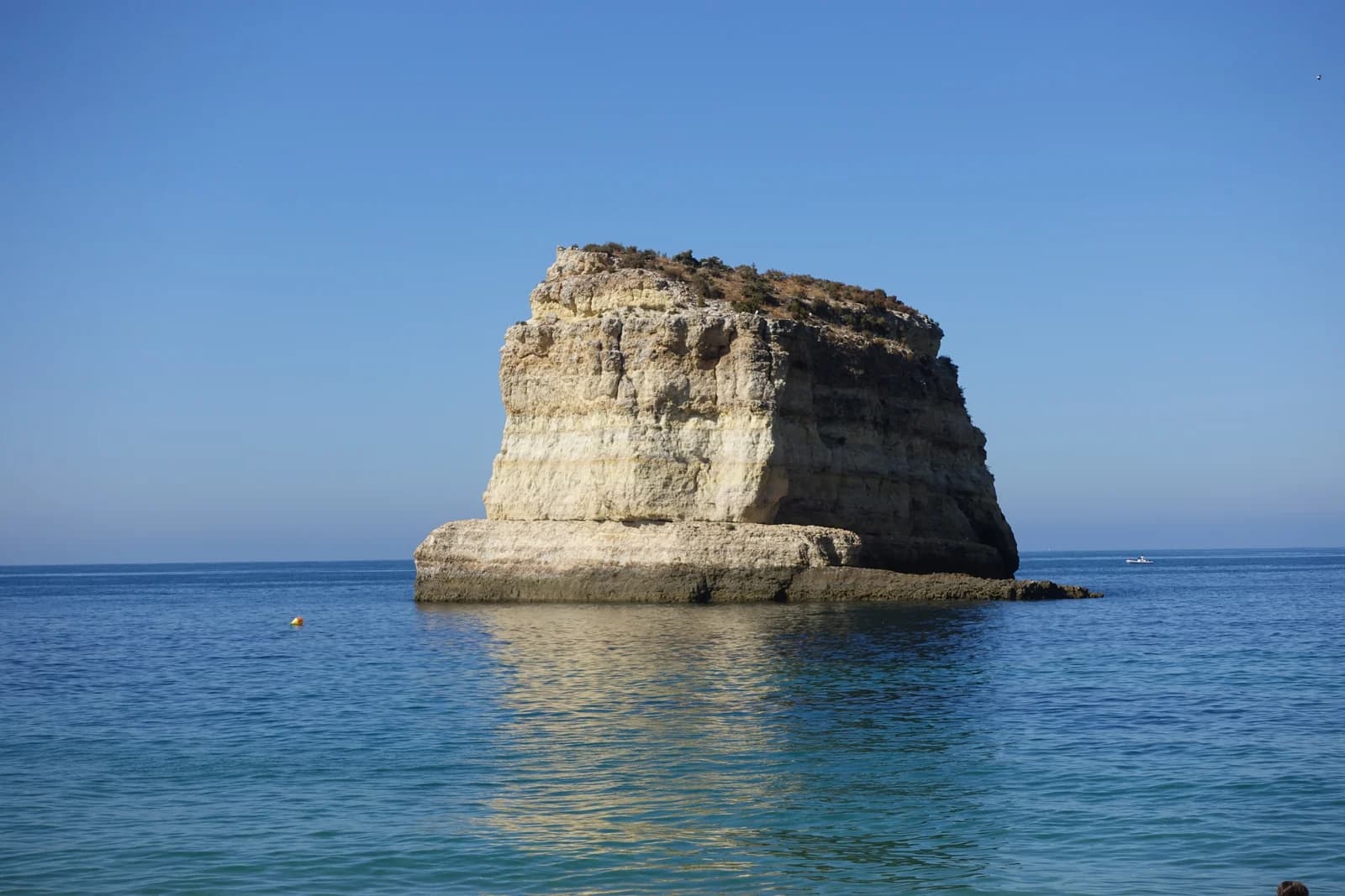 The Leixão das Gaivotas rock stack in calm water off the cliffs between Armação de Pêra and Porches