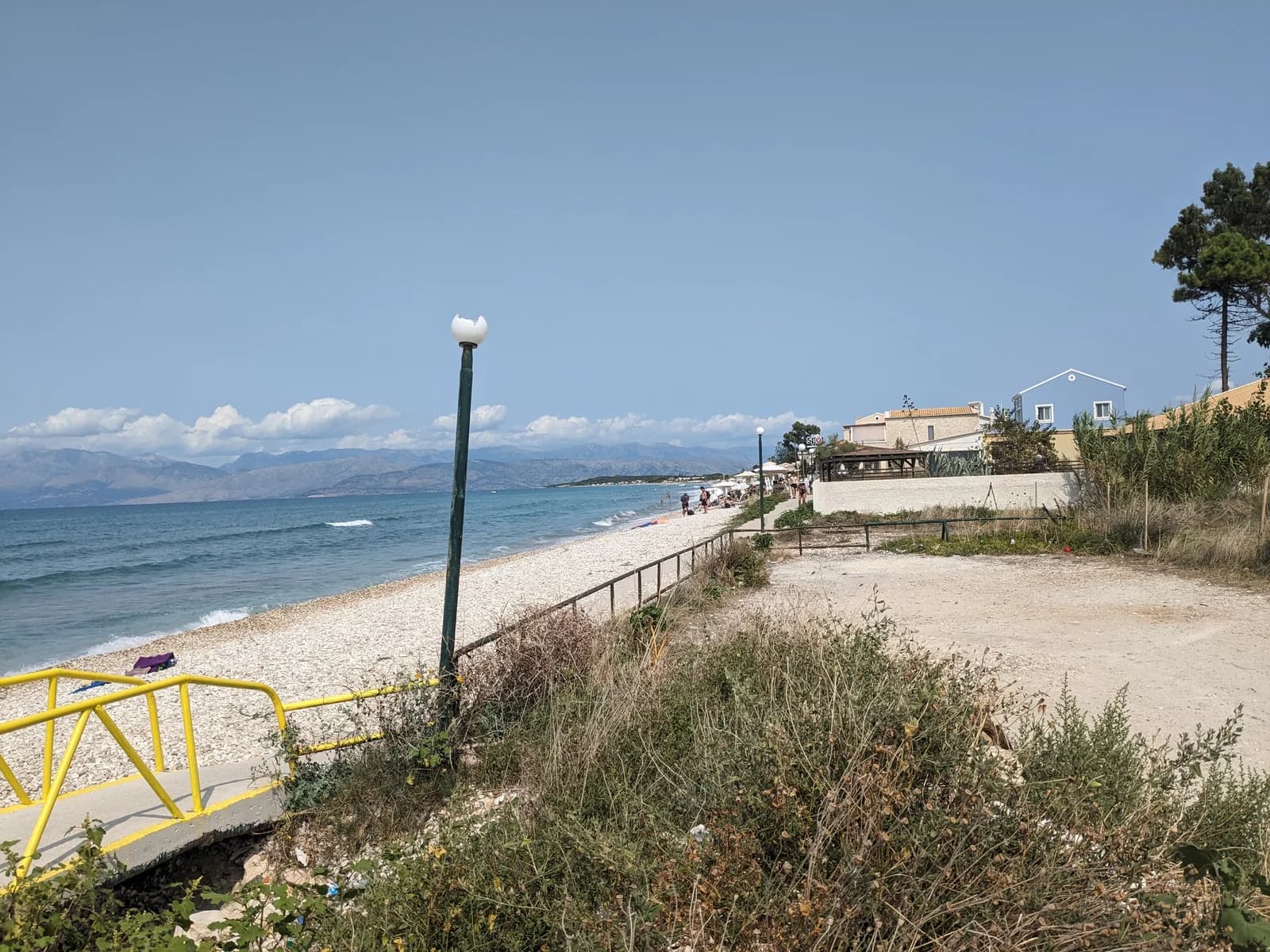 The long shingle beach at Acharavi on Corfu's north coast, with mainland mountains across the water