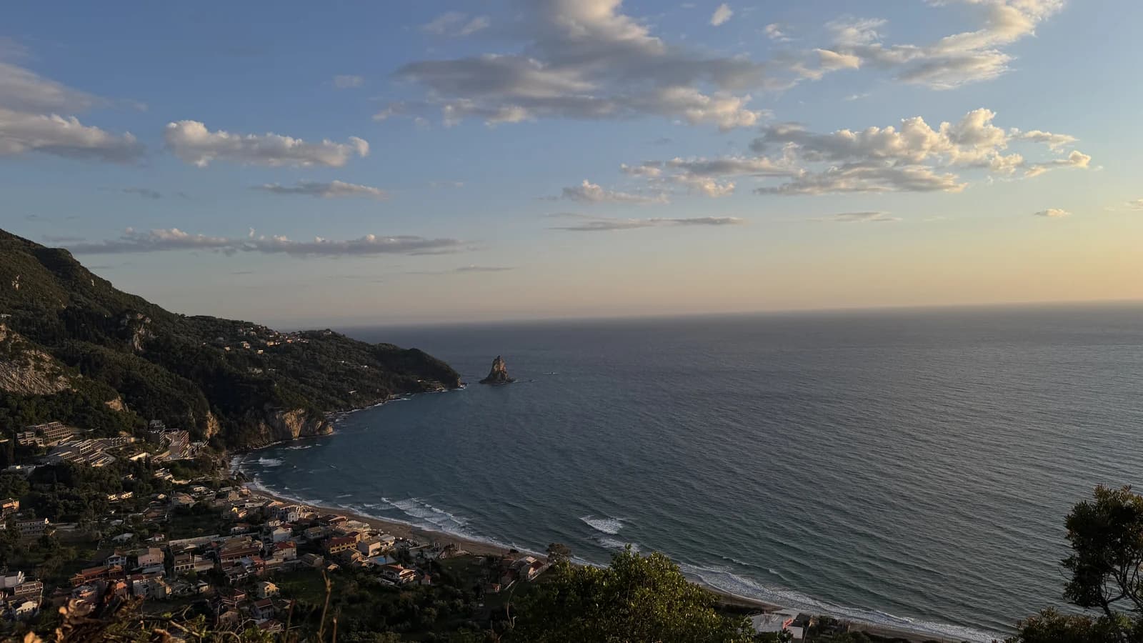 The long beach and sea stack at Agios Gordios on Corfu's west coast, seen from the hillside at sunset