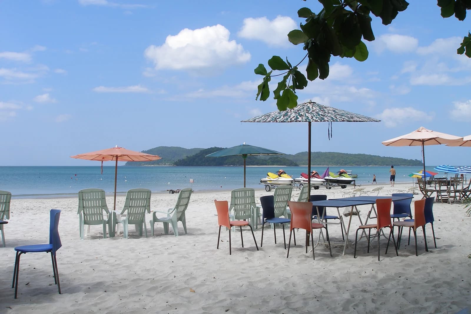 Beach chairs and parasols on the sand at Pantai Cenang, the busiest beach in Langkawi