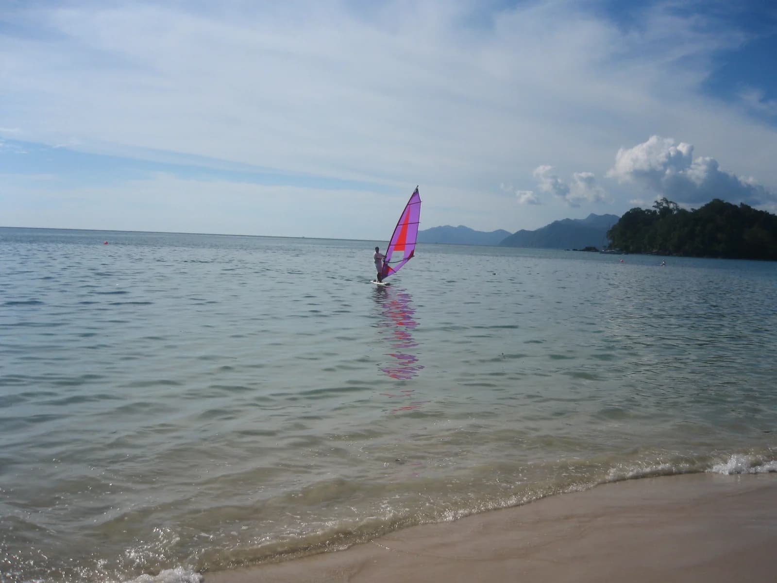 A windsurfer on the calm water of Datai Bay on the north-west coast of Langkawi