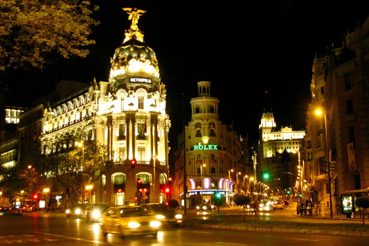 The Metropolis building lit at night on Madrid's Gran Via