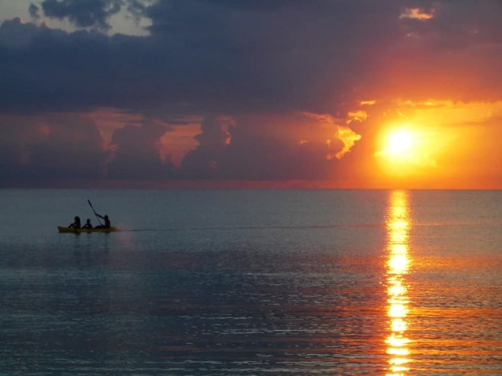 Two paddlers on the calm water at sunset off Seven Mile Beach, Negril