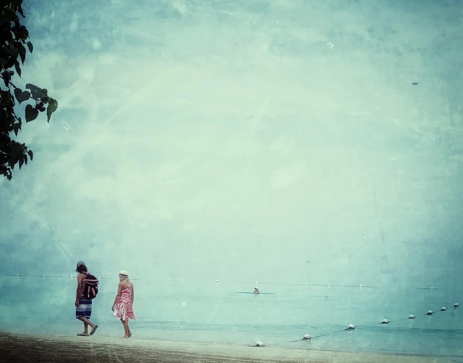 Two people walking the shallows of Negril beach early in the morning