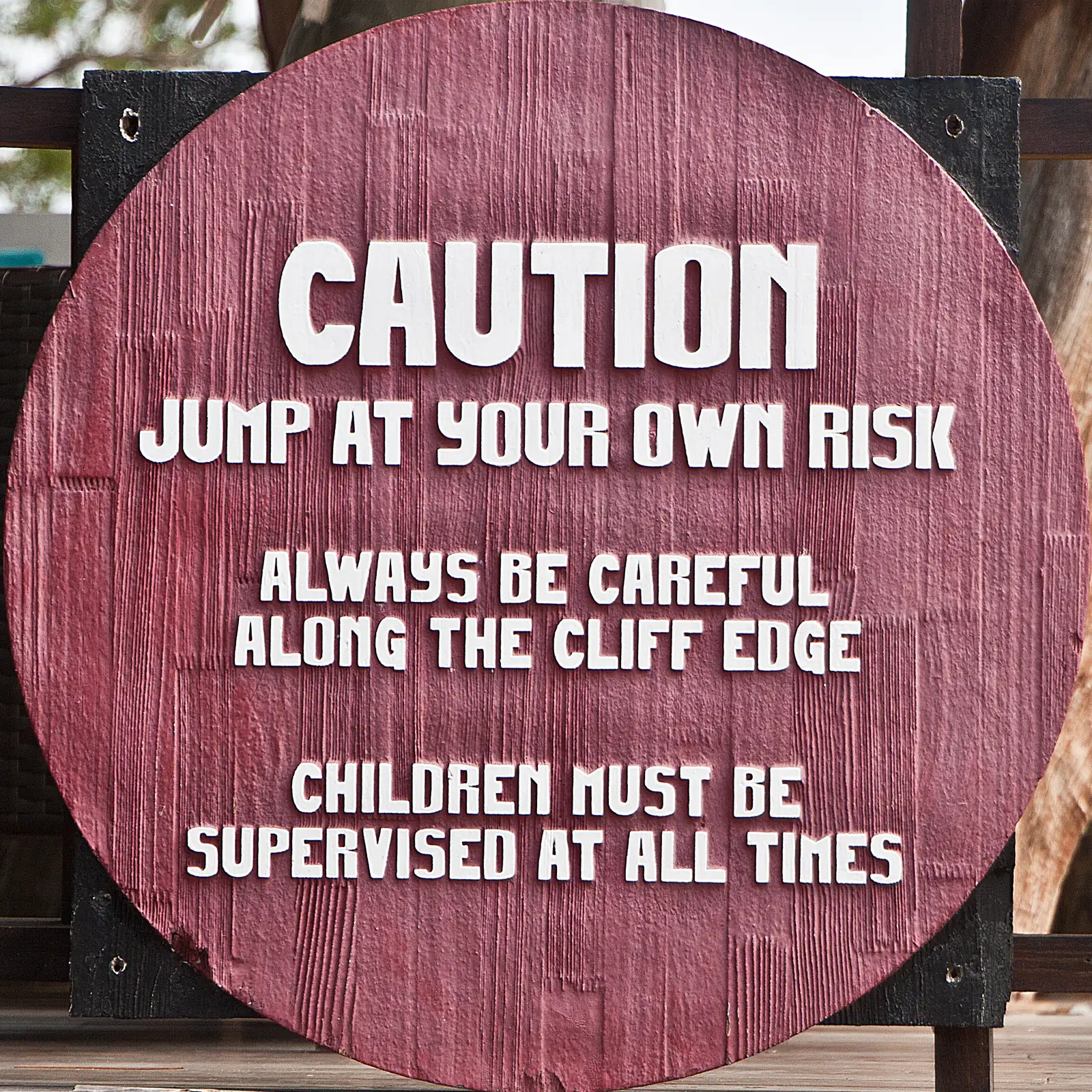 A cliff-edge sign in Negril reading jump at your own risk, children must be supervised at all times