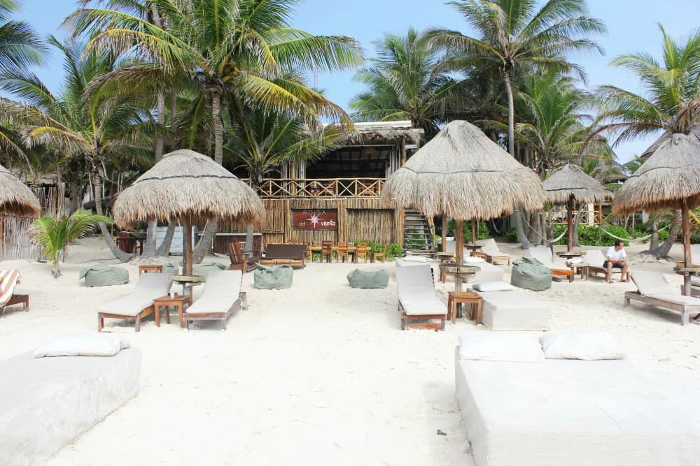 Palapa umbrellas and loungers on the white sand of the Tulum hotel zone