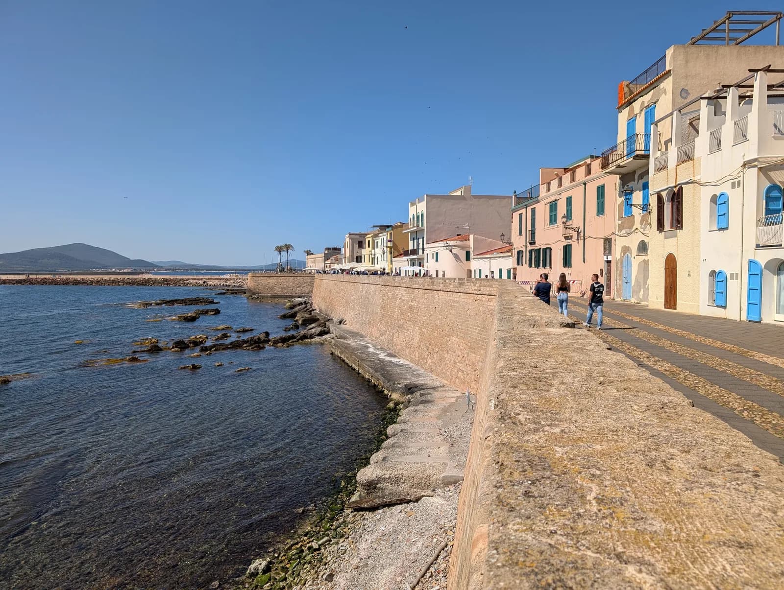 The sea walls and bastions along the Alghero seafront, with the old town houses above
