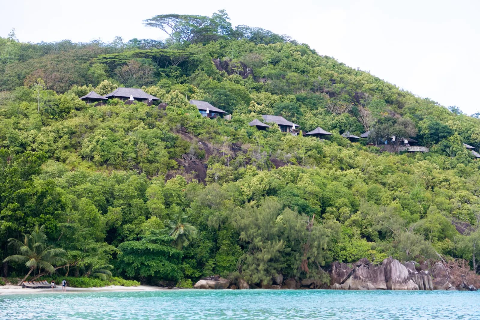 Port Launay bay on Mahé, beside the marine national park, with buildings on the wooded hillside above