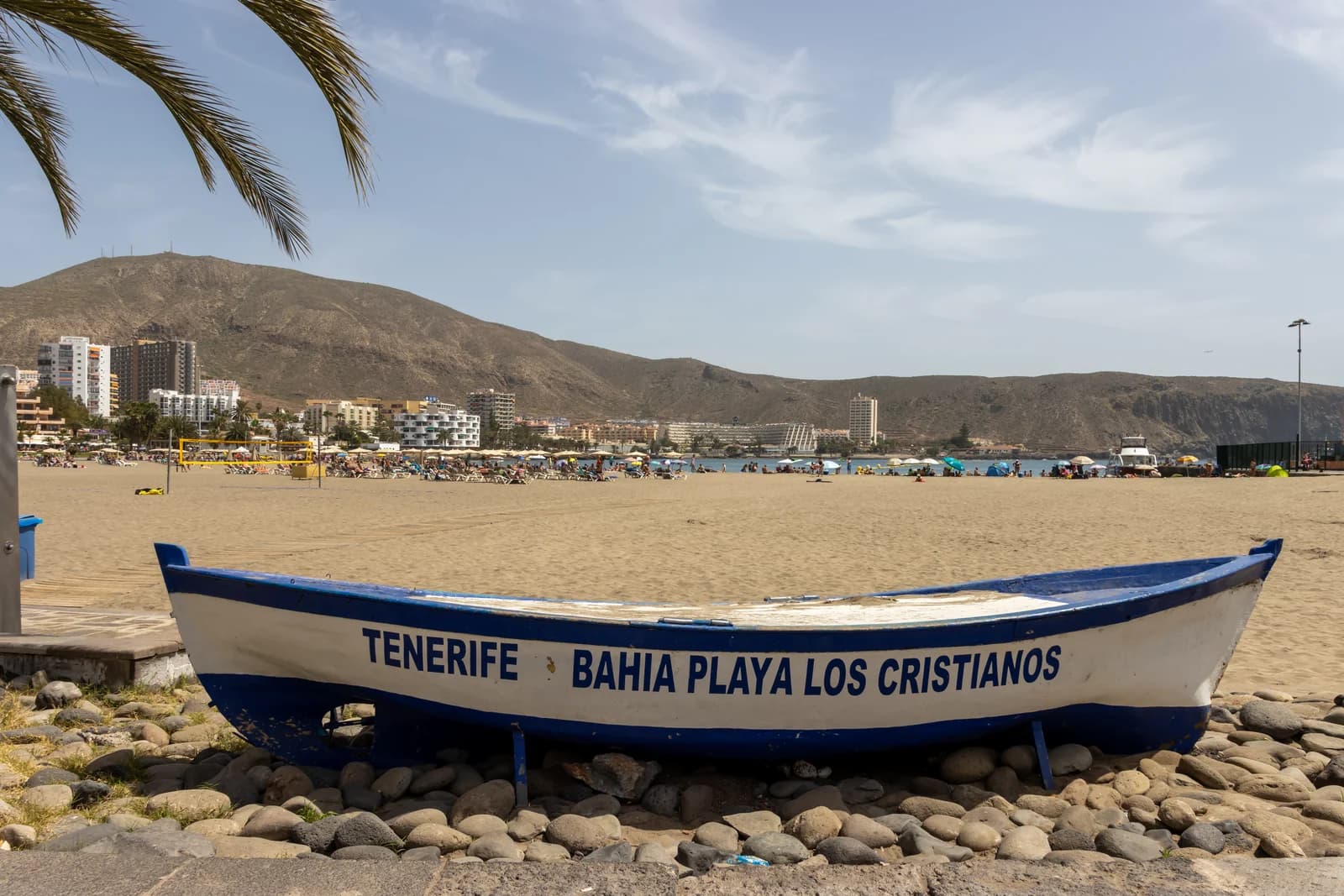 A fishing boat drawn up on the sand at Los Cristianos, with the town's seafront hotels behind the beach