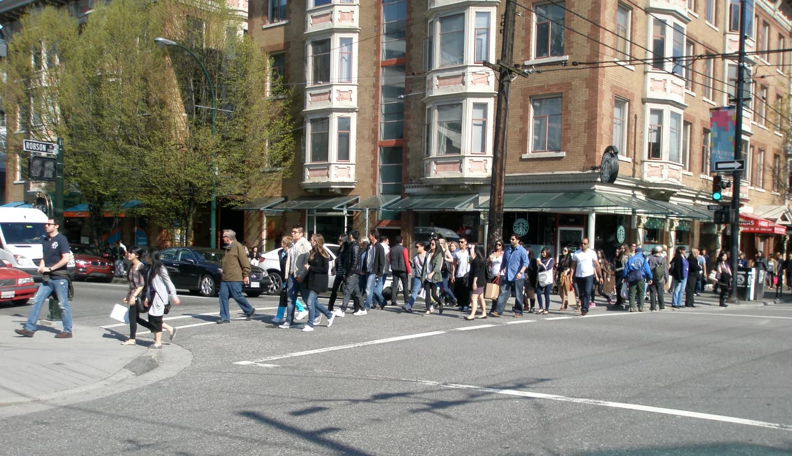 People crossing Robson Street at Thurlow in downtown Vancouver, with the shopping strip behind