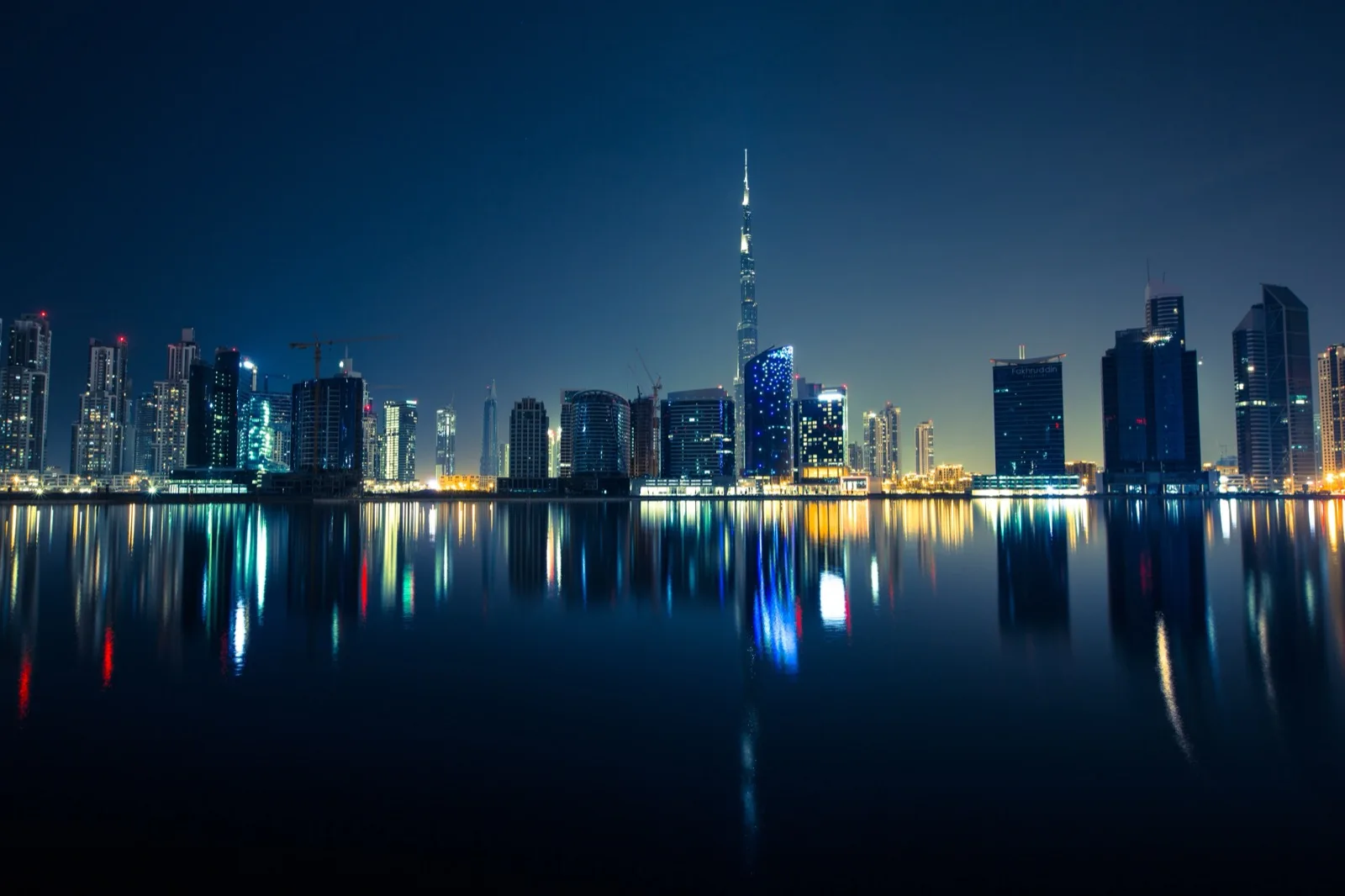 The Dubai skyline at night with the Burj Khalifa reflected in the water