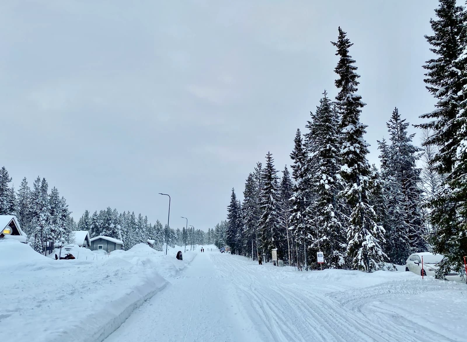 A snow covered road past wooden cabins and deep drifts at Akaslompolo below Yllas fell