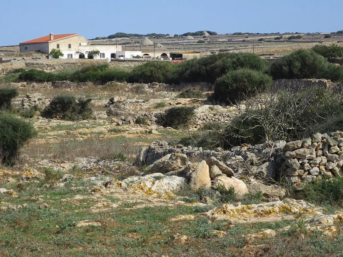 A whitewashed Menorcan farmhouse among dry-stone walls and scrub, the countryside where the island's rural boutique hotels stand