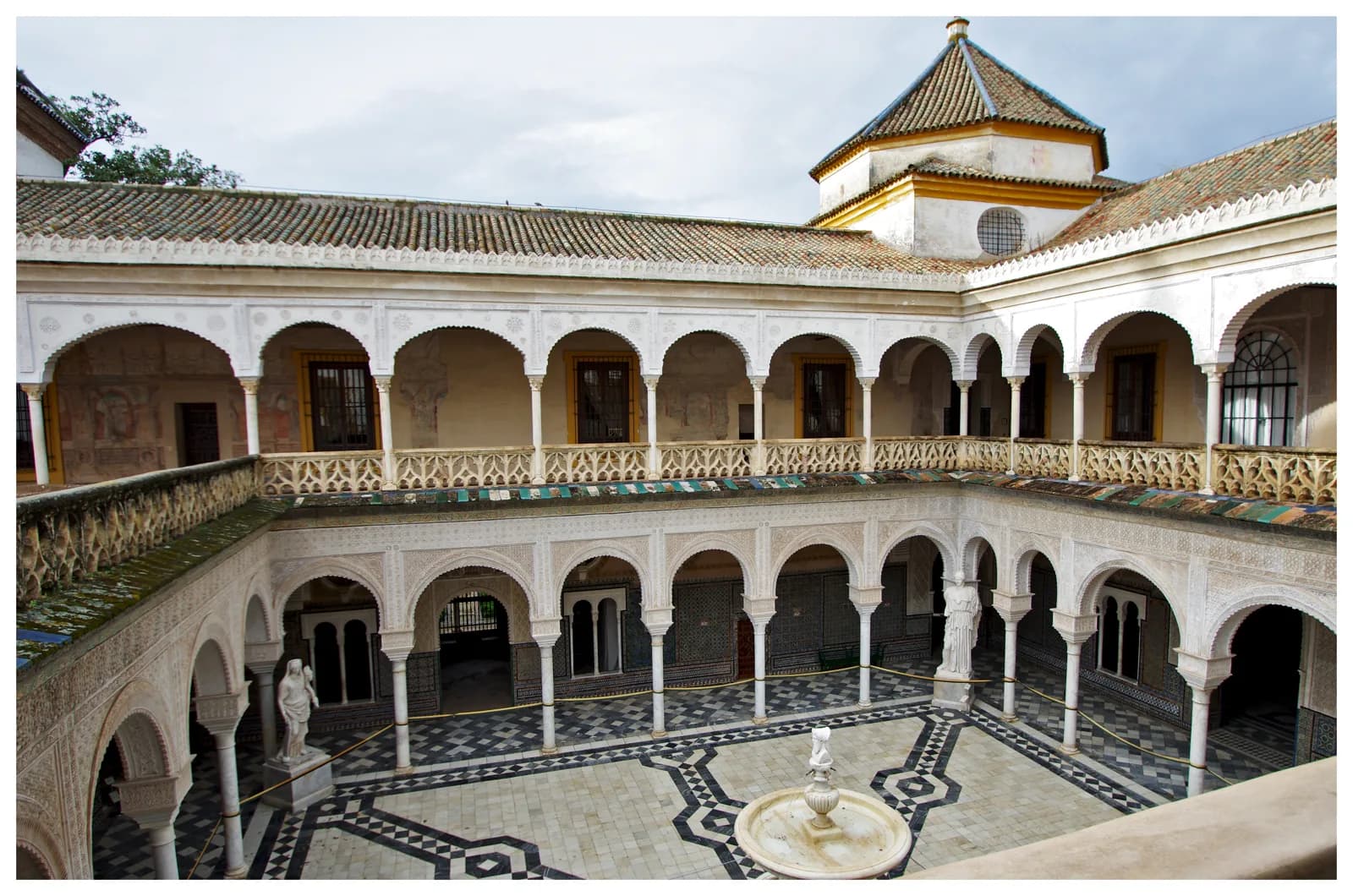 A columned courtyard with a fountain in a Sevillian palace house, the layout most Seville hotels convert