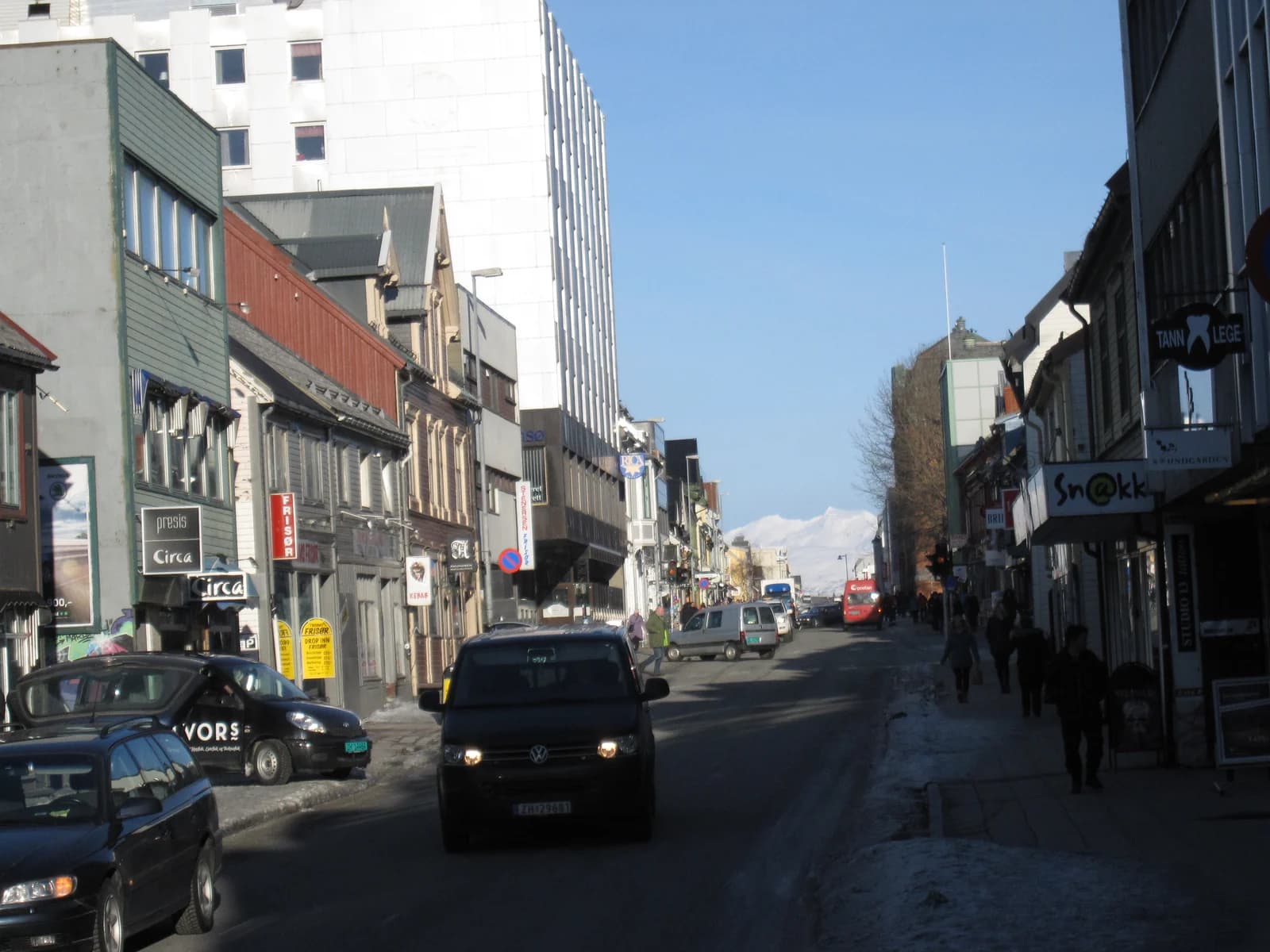 Storgata in the Tromso town centre, shops on both sides and snow covered mountains at the end of the street