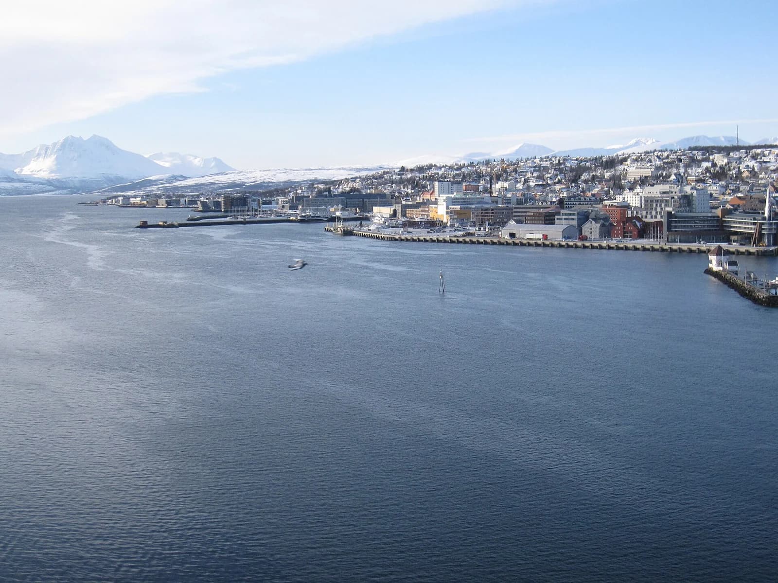 Southern Tromso seen across the water, the town spread along the shore below snow capped Arctic mountains