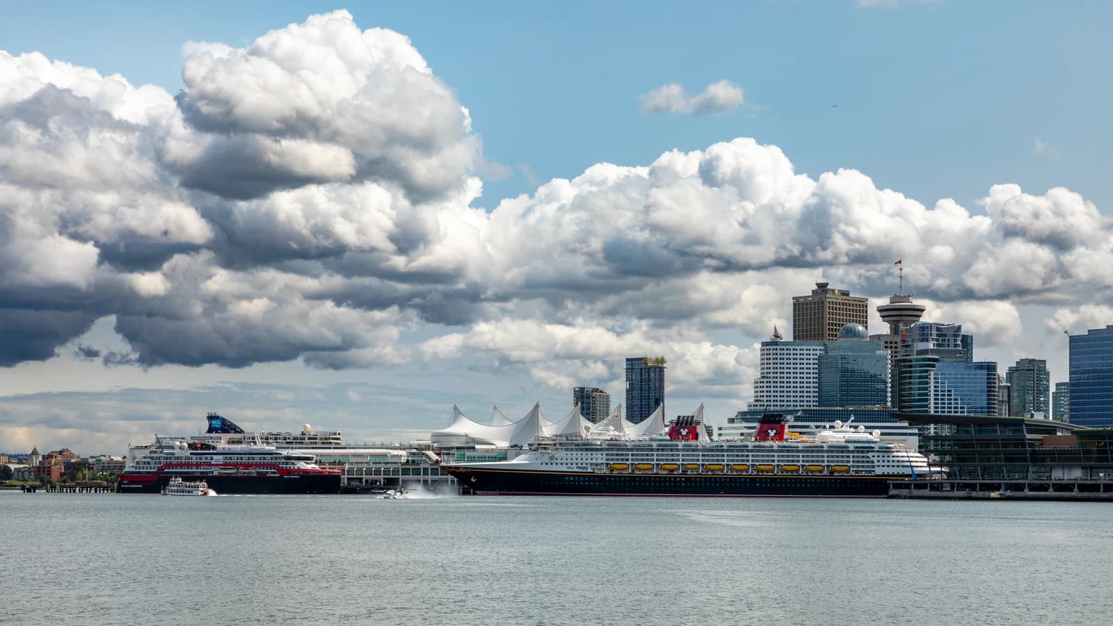 Canada Place under its white sail roof with ships alongside and the downtown Vancouver skyline behind