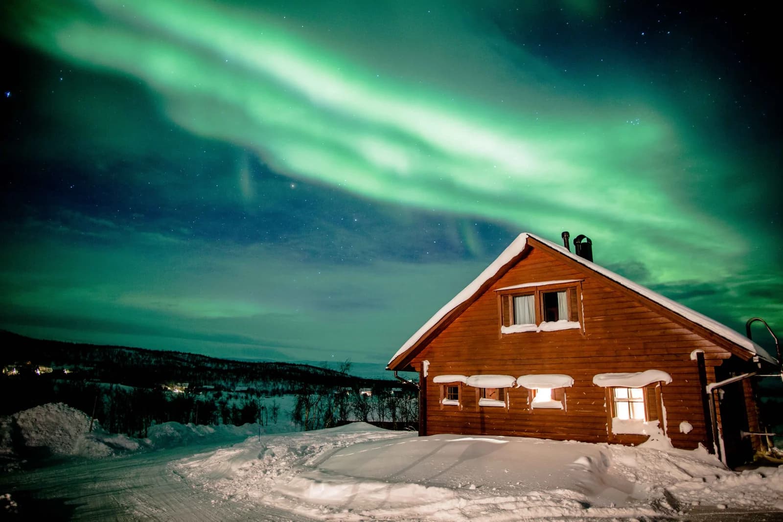 Green aurora over wooden chalets beside a frozen lake at Kilpisjarvi in Finnish Lapland
