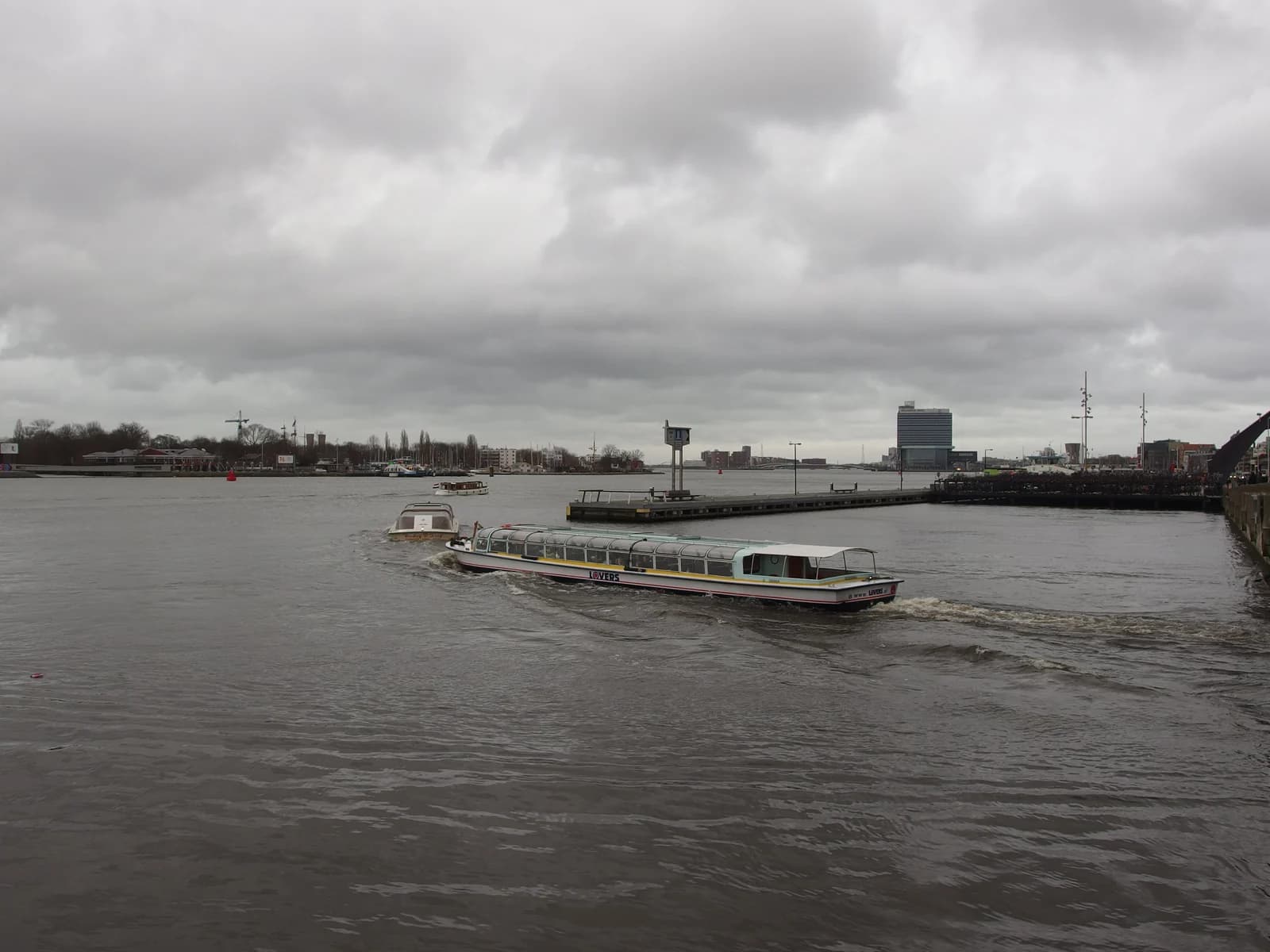 Boats crossing the IJ river between Centraal Station and Amsterdam Noord on a grey day