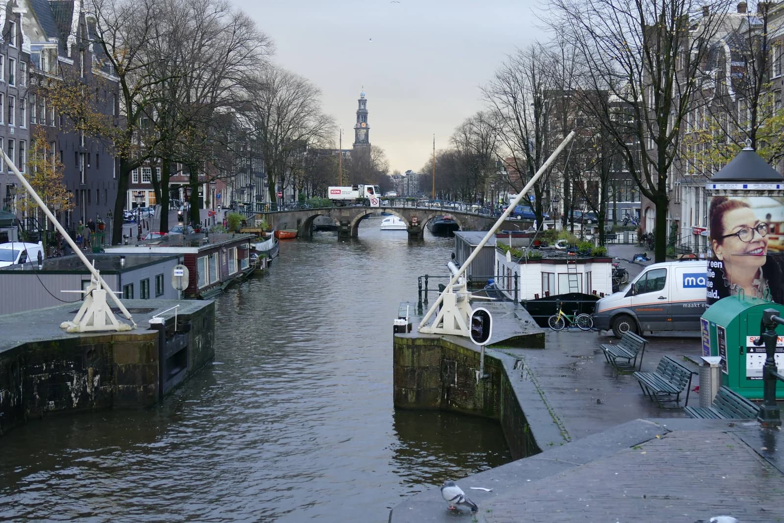 The Prinsengracht canal with houseboats and an arched bridge, and the Westerkerk tower beyond