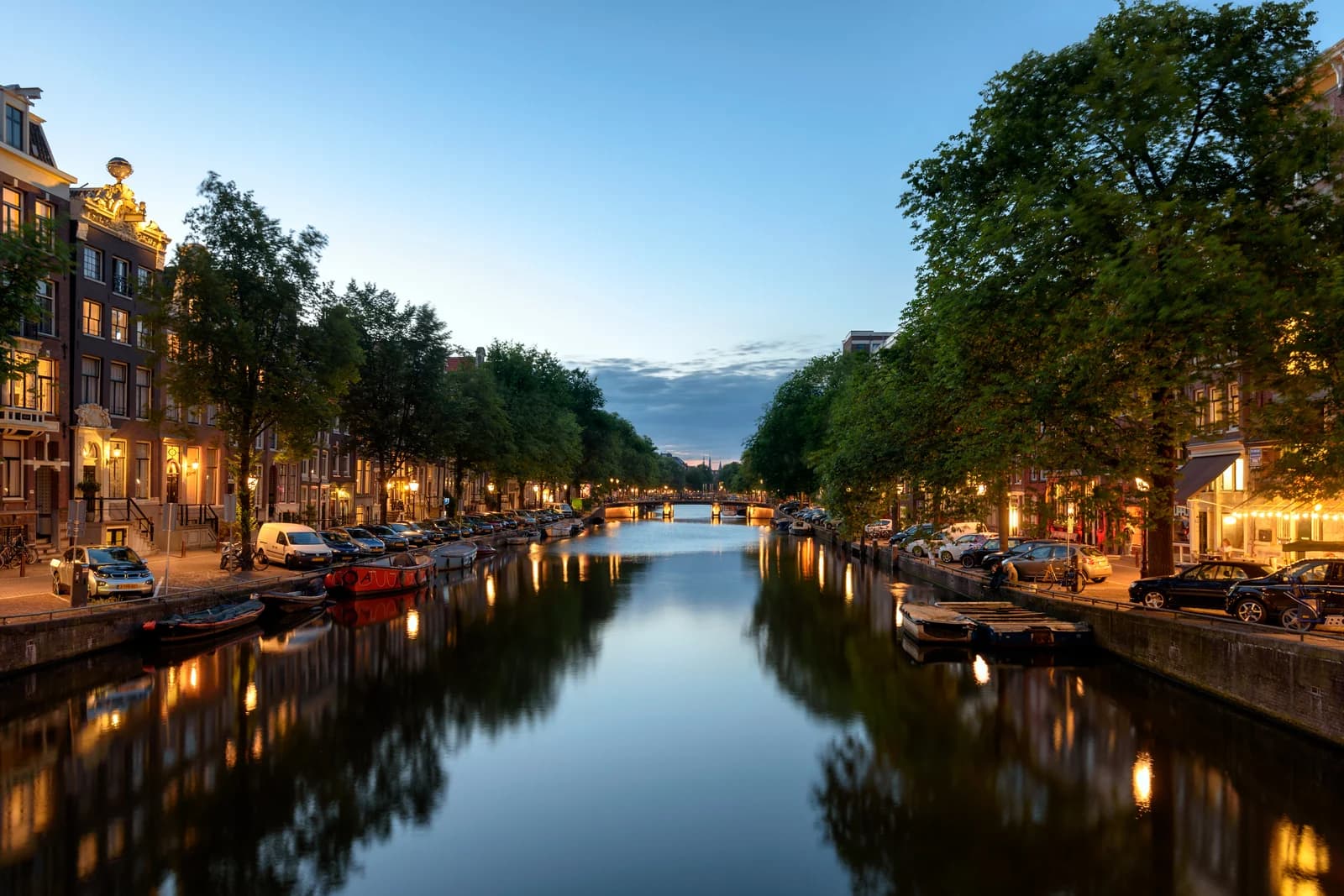The Singel canal in central Amsterdam at dusk, with lit canal houses reflected in the water
