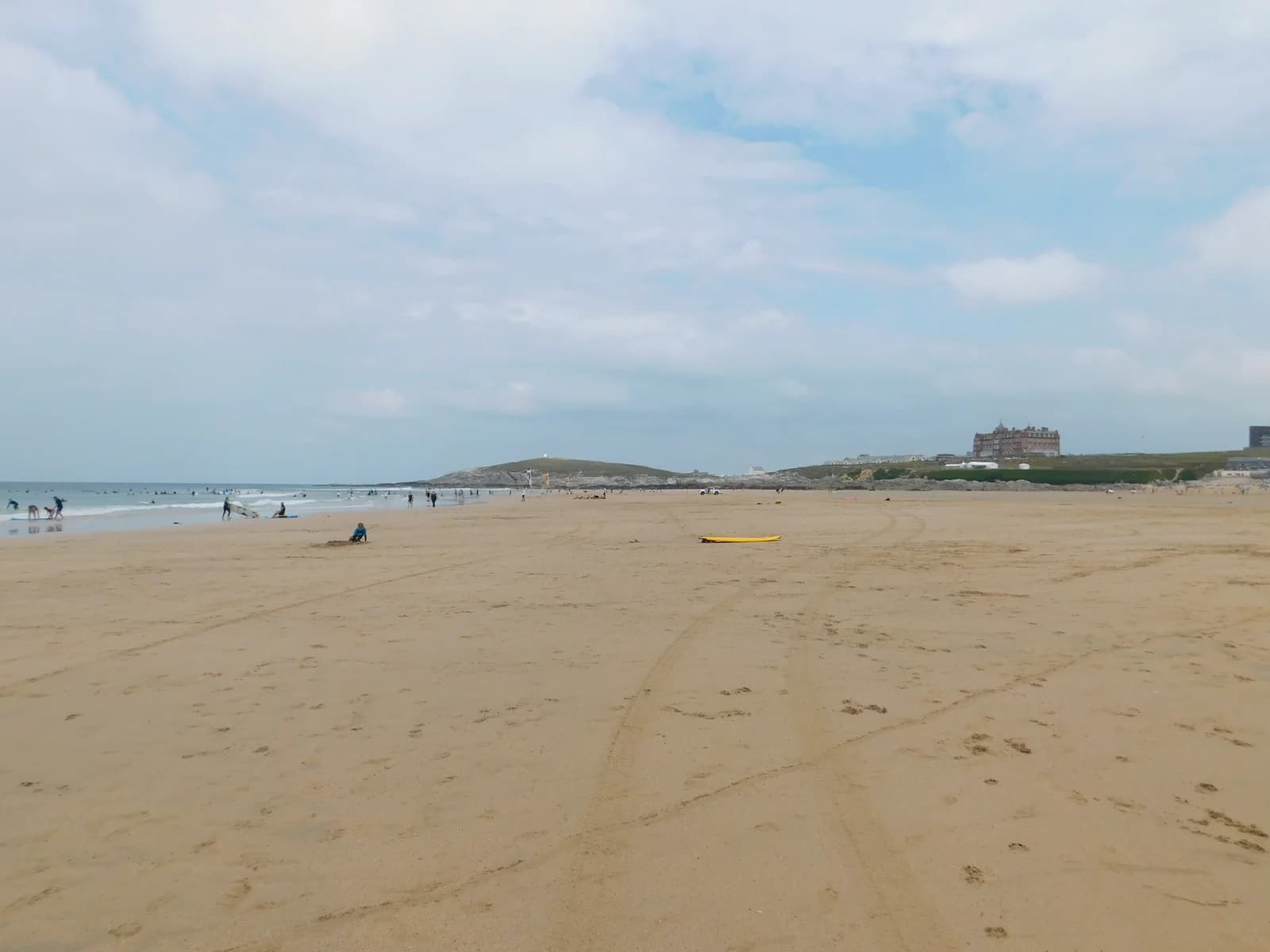The long sand of Fistral Beach in Newquay with surfers at the water's edge
