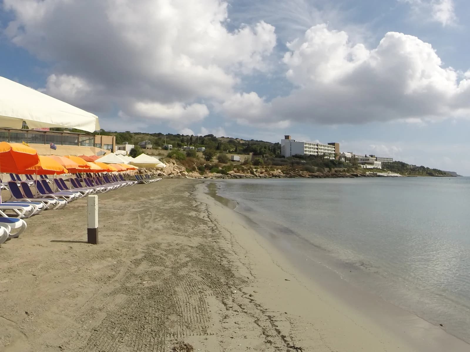 Sunbeds and umbrellas on the sand at Għadira beach on Mellieħa Bay