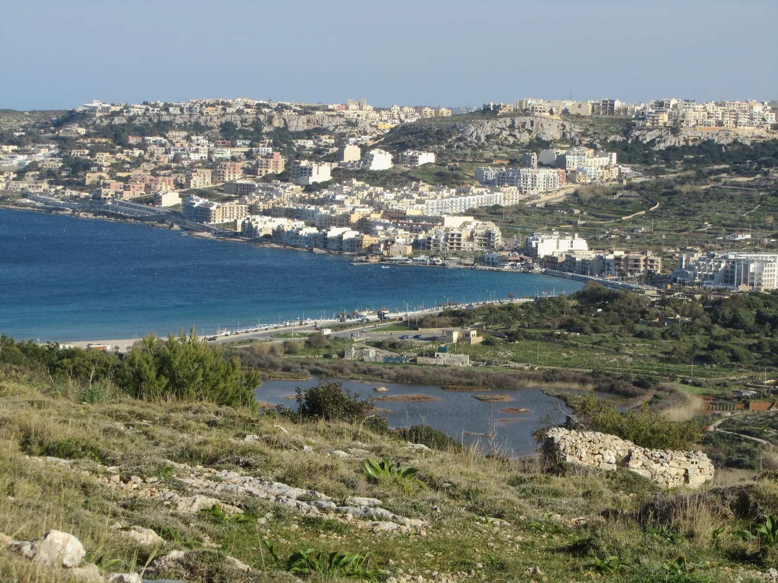 The Għadira wetland reserve with the curve of Mellieħa Bay and Mellieħa town behind it
