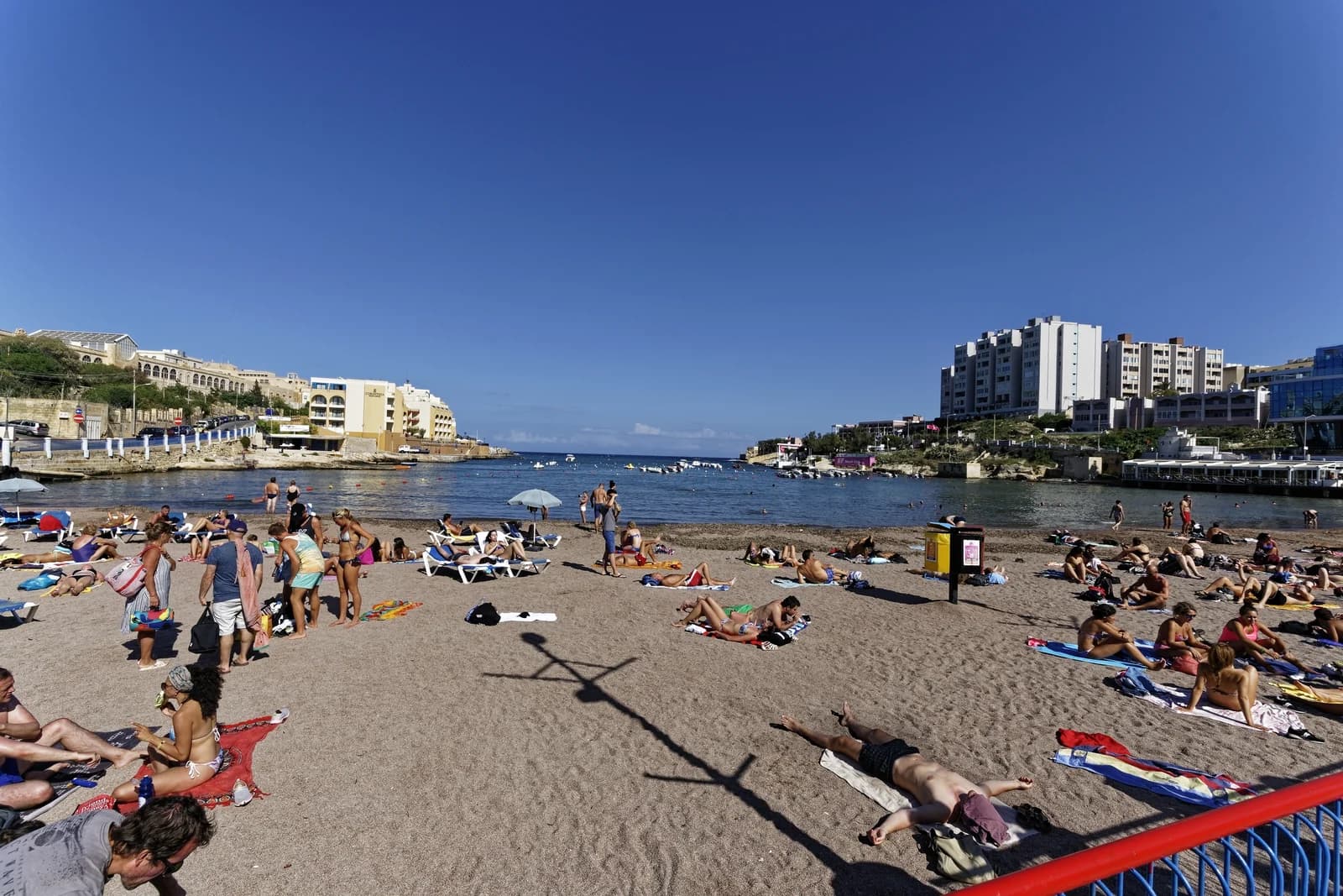 Swimmers and sunbathers on the sandy beach at St George's Bay in St Julian's