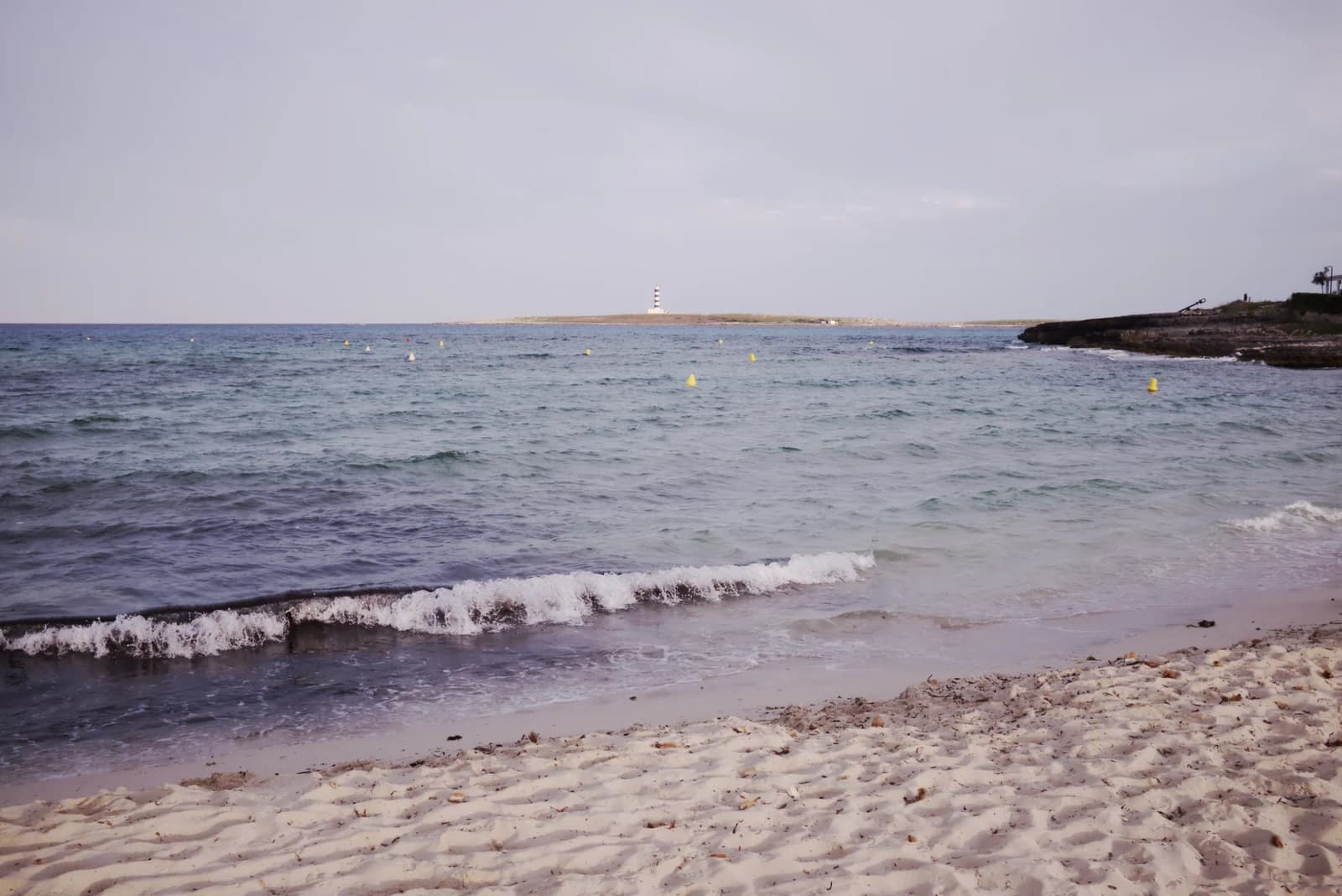 The beach at Punta Prima with the Illa de l'Aire lighthouse on the horizon
