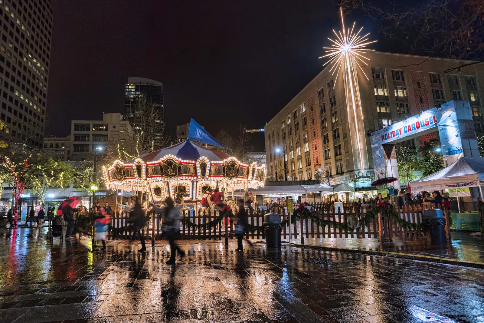 The lit holiday carousel in Westlake Park in downtown Seattle on a wet evening