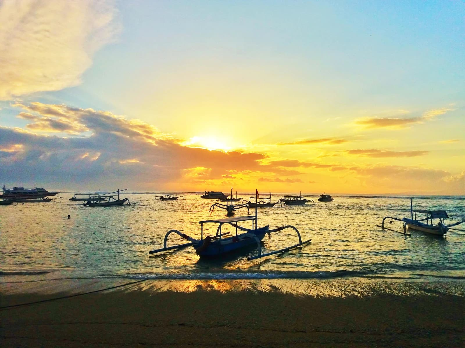Jukung outrigger boats on the shallow water off Sanur beach at sunrise, the quieter of the Bali hotel strips