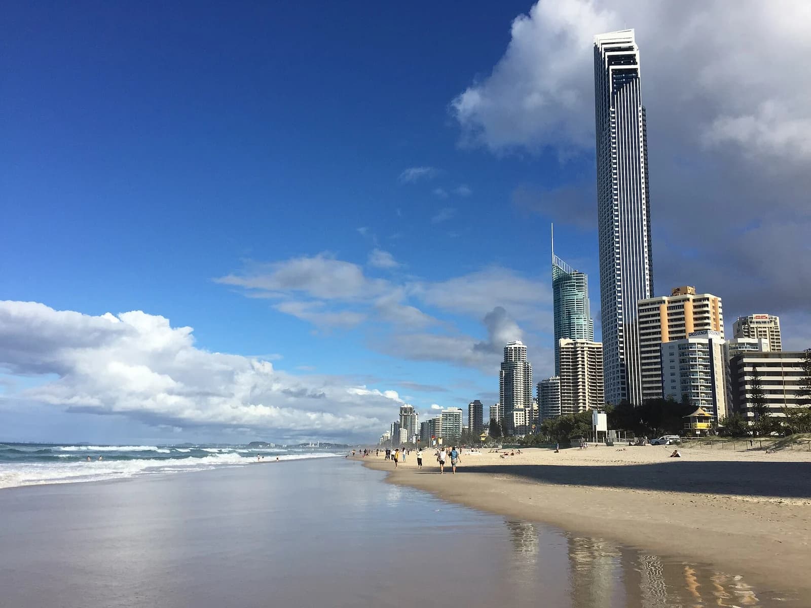 Surfers Paradise beach on the Gold Coast in winter, the wide sand backed by the wall of apartment towers families book