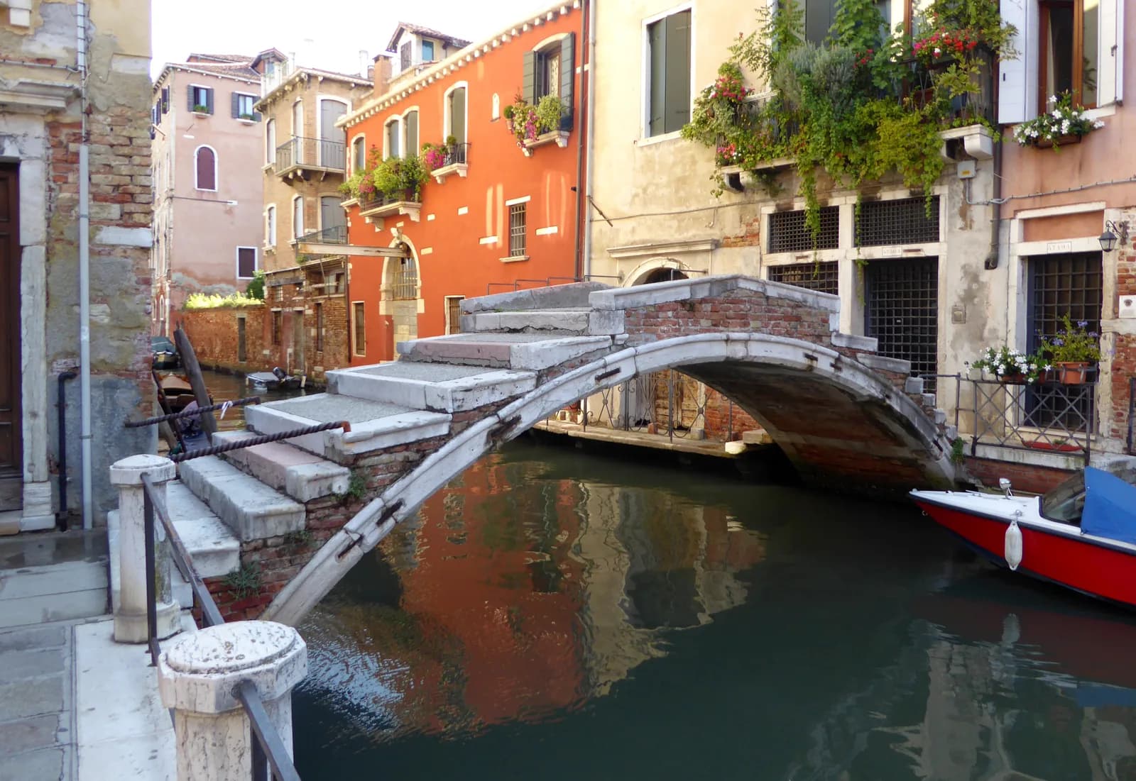 A stepped stone bridge over a canal in Cannaregio, the crossing a family with a pushchair makes between Venice hotels