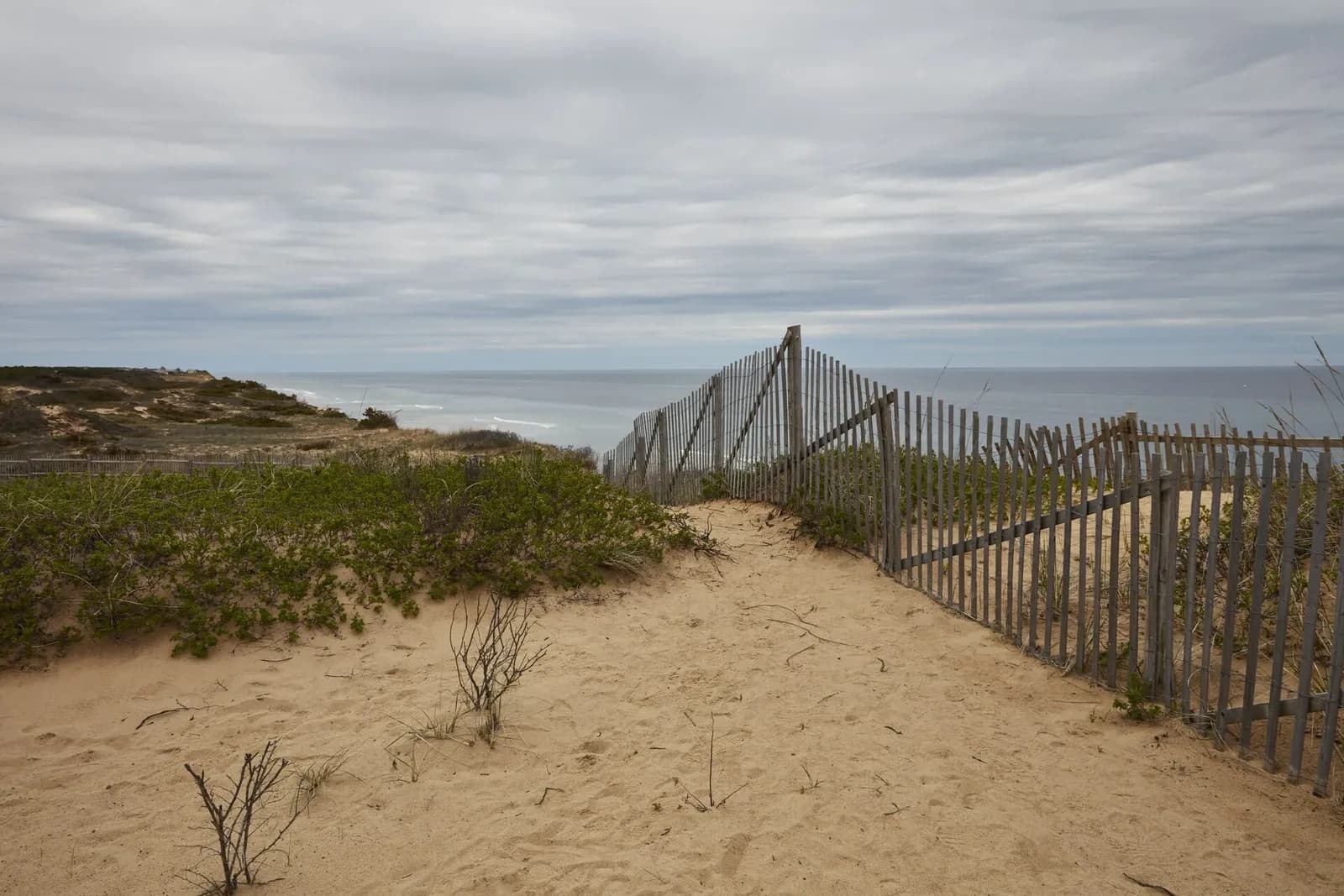 A fenced sand path through the dunes to the beach on the Cape Cod National Seashore near South Wellfleet