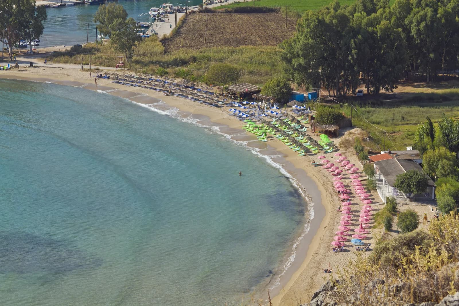 Rows of parasols and sun loungers along the curving sand at Pilot Beach, Georgioupoli, on the north coast of Crete