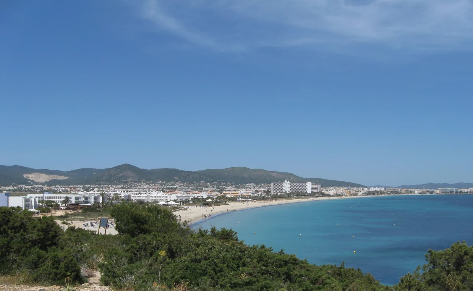 The bay at Playa d'en Bossa on Ibiza, with resort hotels running along the sand above turquoise water