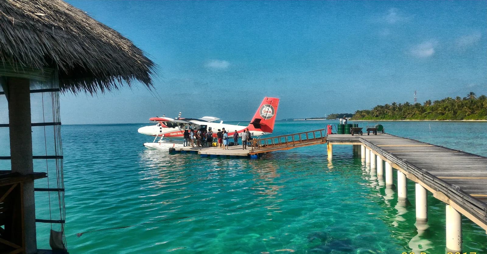 Passengers boarding a Trans Maldivian seaplane at a resort jetty, the transfer no all-inclusive plan covers