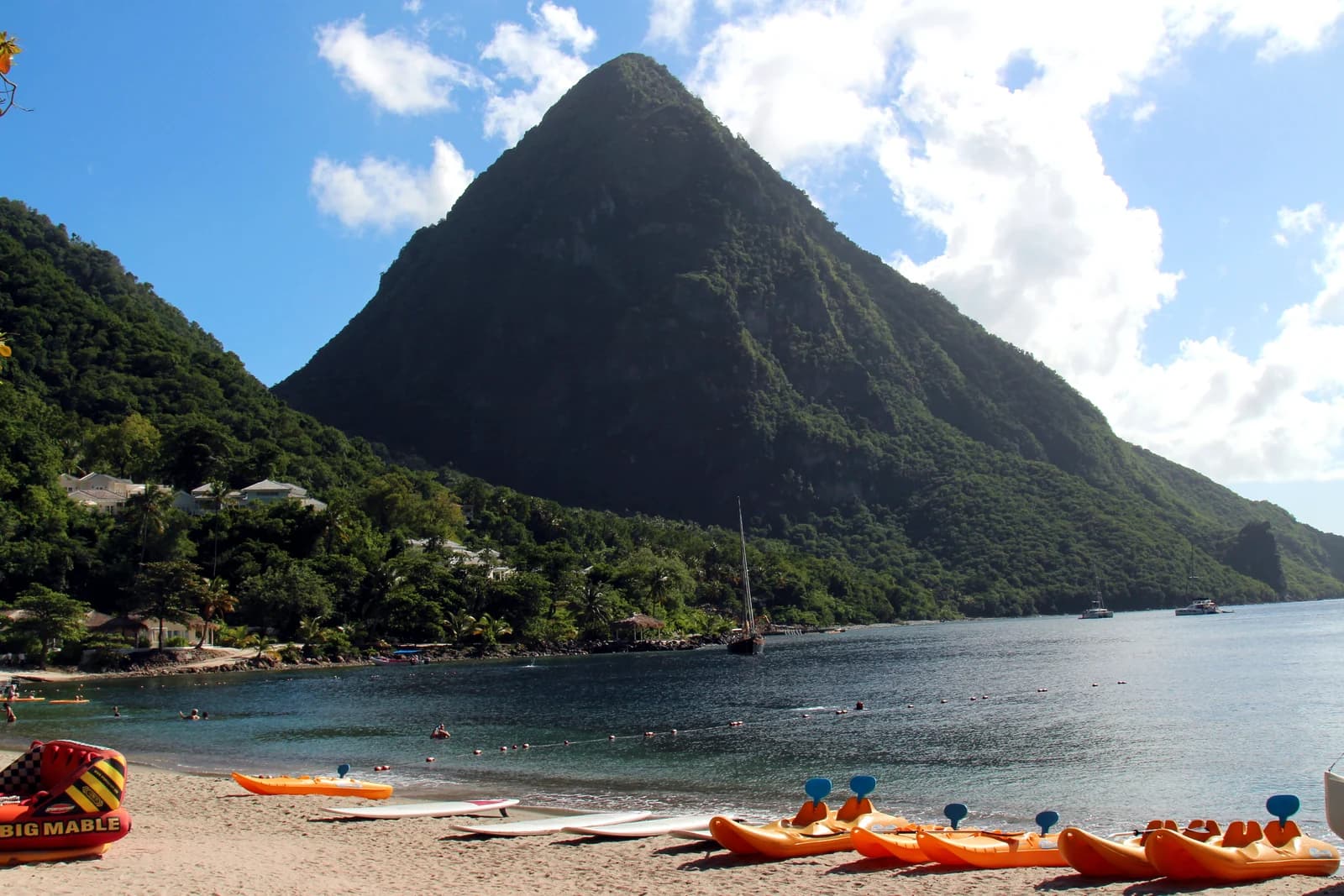 Kayaks and paddleboards on the sand at Sugar Beach in Saint Lucia, with a forested Piton rising behind the bay