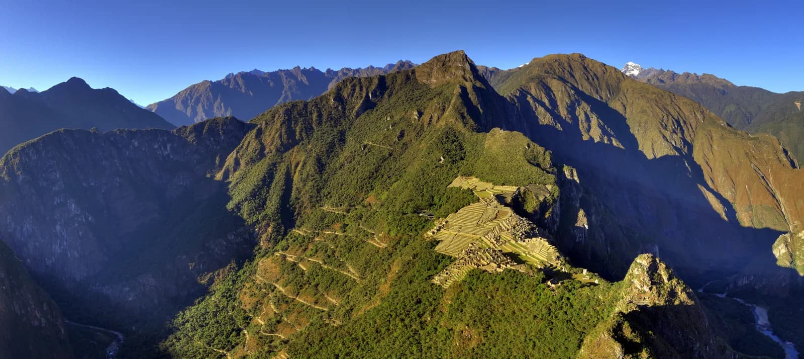 Panorama of the Machu Picchu citadel under clear dry-season skies with Huayna Picchu rising behind
