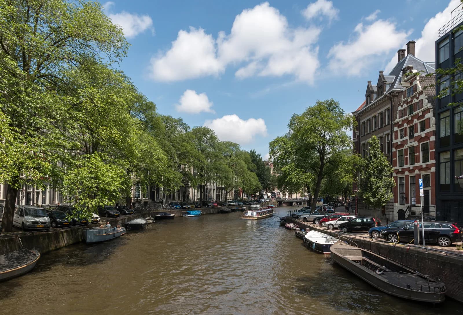 Herengracht canal in Amsterdam lined with gabled houses, moored boats and trees