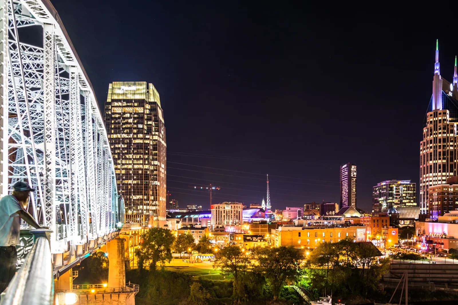 The lit pedestrian bridge and Nashville skyline across the Cumberland at night