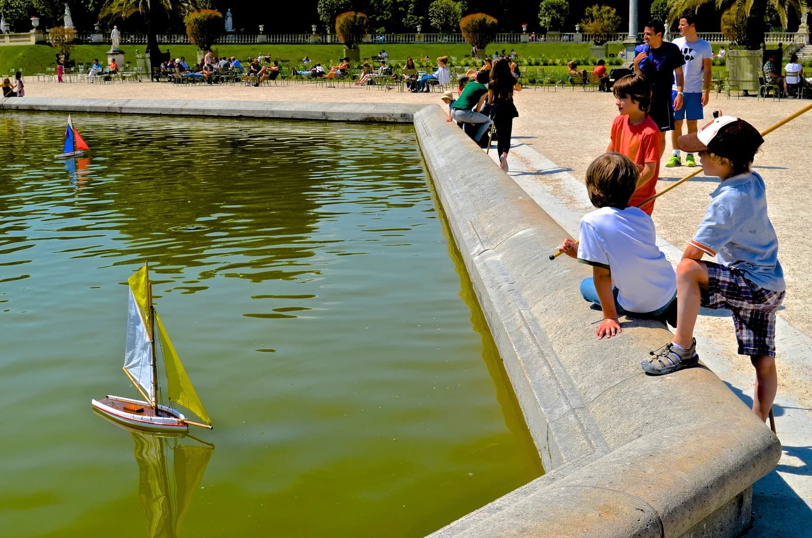 Children sailing model boats on the basin in the Jardin du Luxembourg in Paris