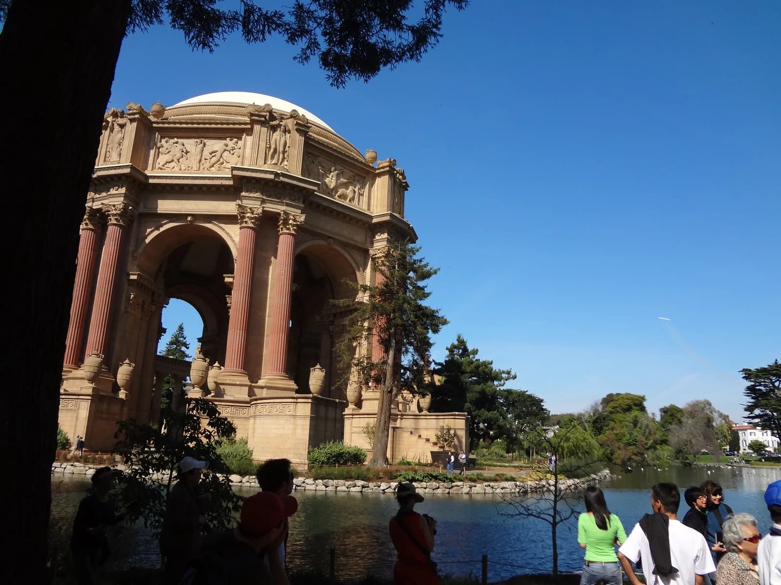 Visitors walk beside the lagoon in front of the Palace of Fine Arts rotunda on a clear day