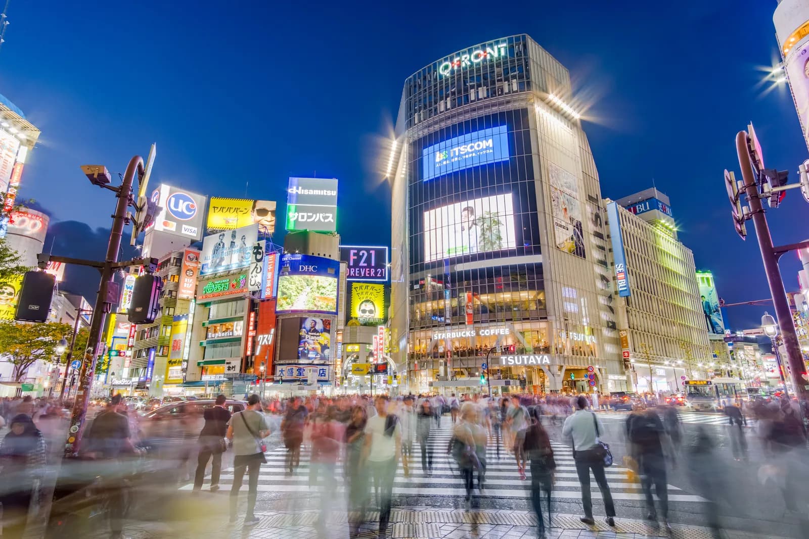 Neon Shibuya Crossing at dusk with crowds streaming across the intersection