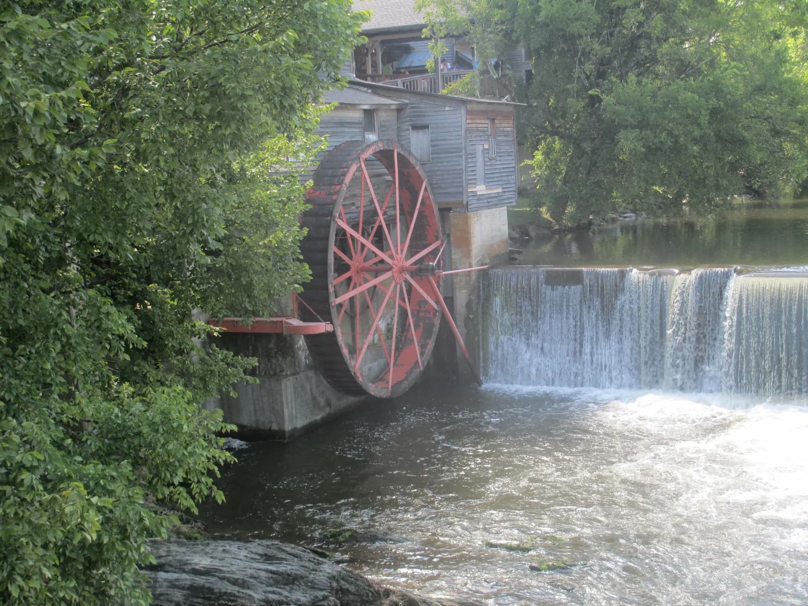 The red waterwheel of the Old Mill turning on the Little Pigeon River beside Patriot Park